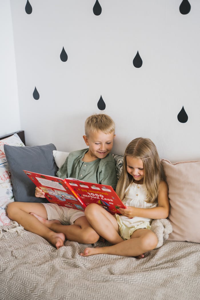 Photograph of a Kids Reading a Book on the Bed
